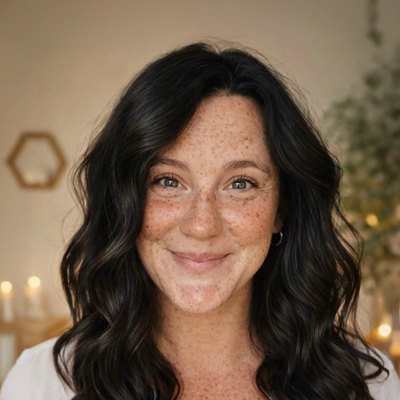An individual with shoulder‑length wavy dark hair wearing a light‑colored top