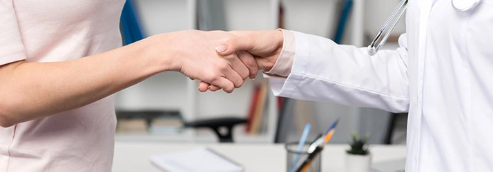 Two individuals shaking hands in a clinical setting