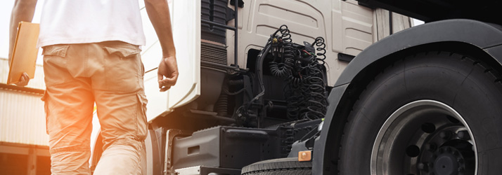 Driver walking toward a semi-truck, representing DOT physical exams and commercial driver certification.